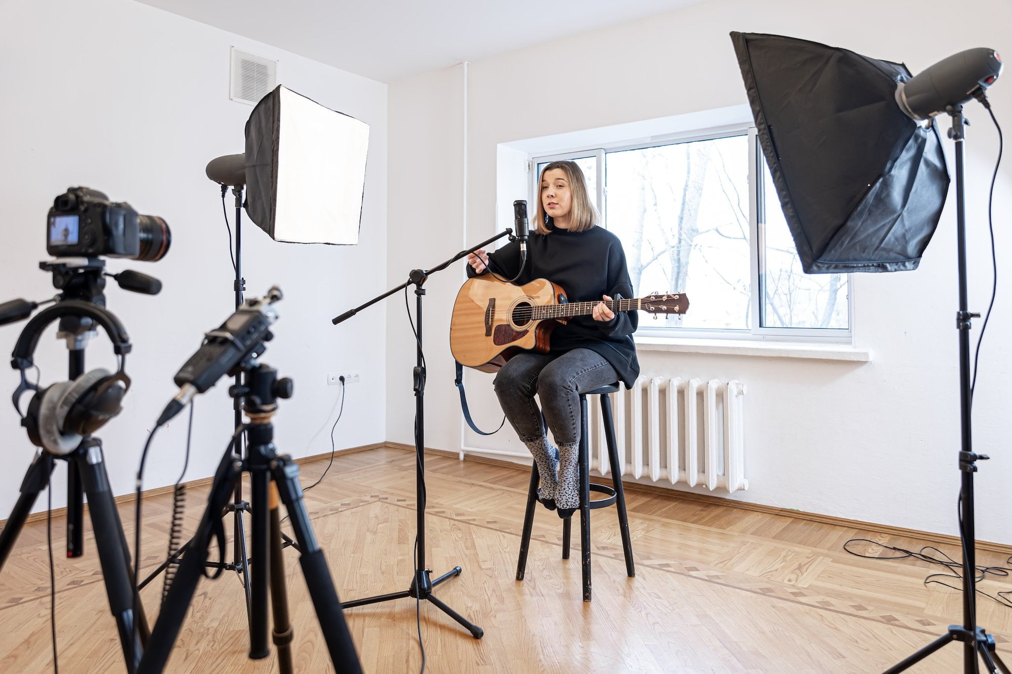 A young girl plays the guitar, recording video and sound.