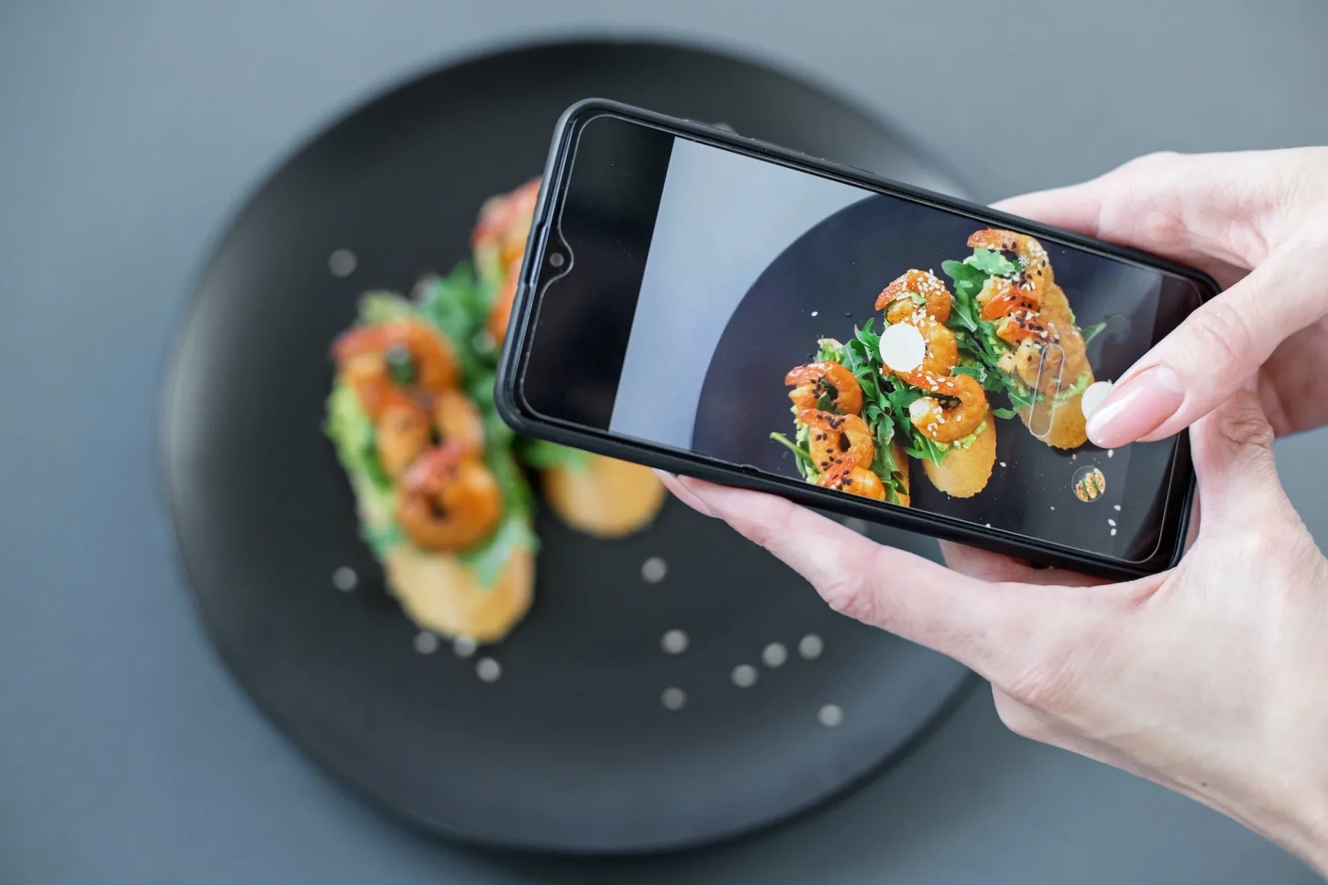 Picture for lifestyle design. A girl takes pictures of a bruschetta from a buffet on her phone